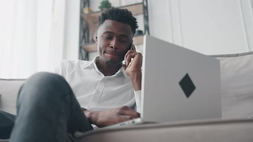 Young Adult Works and Talks on Smartphone at Home