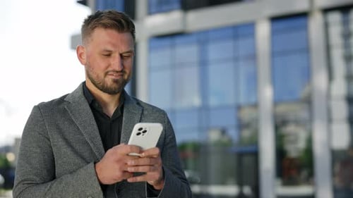 Man Using Phone in Front of Modern Building