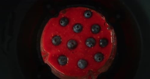 Alternative view of mixing dietetic beverage with fresh biologic blueberries and raspberries in sl