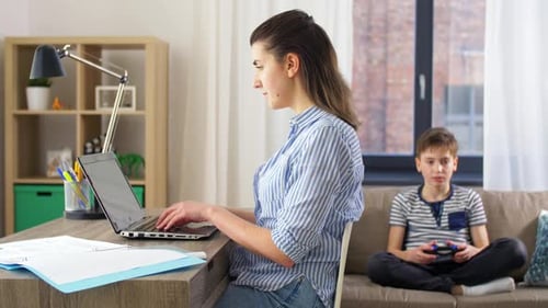 Konzept für Familie, Fernarbeit und Menschen — Mutter mit Papieren und Laptop bei der Arbeit und Sohn Pl...