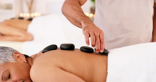 Senior woman in spa, zen massage with hot stones for wellness or luxury beauty therapist in Dubai