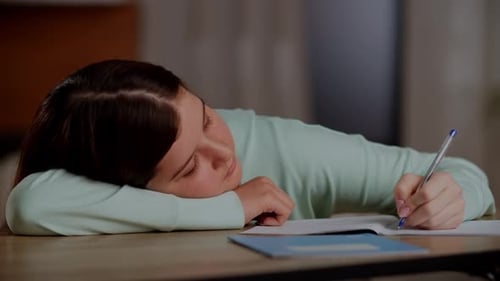 The Girl Lies on the Desk and Tries to Finish Her Homework A Tired Brunette Girl Lay Down on the