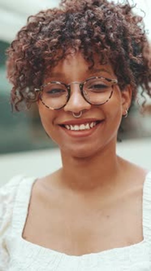 Close-up portrait of a young woman in glasses smiling while looking at the camera