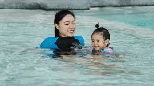 glückliche Mutter mit einem kleinen Mädchen in einem Schwimmbad