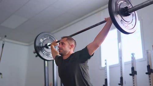 Determined Athlete Lifting a Heavy Barbell Overhead