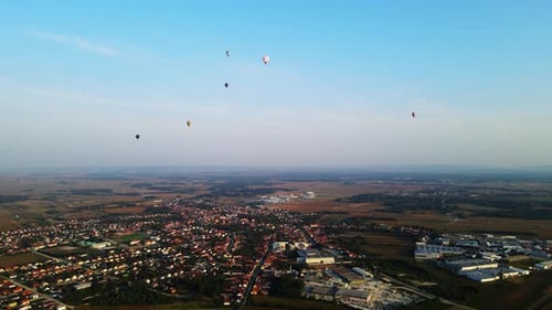Stunning 4K aerial footage of a drone filming hot air balloons. Flying over farming fields and river