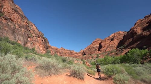 Young Lonesome Woman Walking on a Desert Trail Under Red Rock Sandstone Hills in Utah, St. George Hi