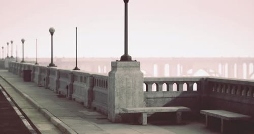 Quiet Waterfront Promenade with Vintage Lampposts and Distant Bridge at Dawn