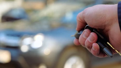 Nahaufnahme einer Frau in der Hand, die den Schlüssel eines neuen Autos hält, sicheres Schloss für den Transport, verschwommener Hintergrund des Autos