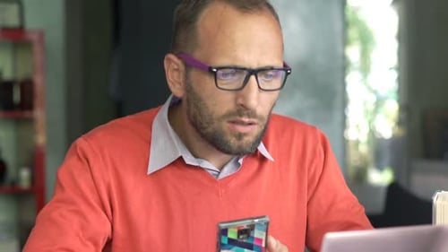 Focused Man Using Phone and Laptop Indoors