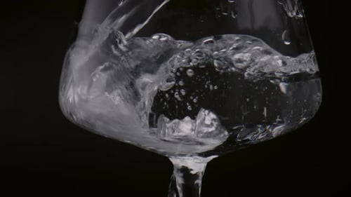 Stream Water Pouring Glass on Black Background Closeup