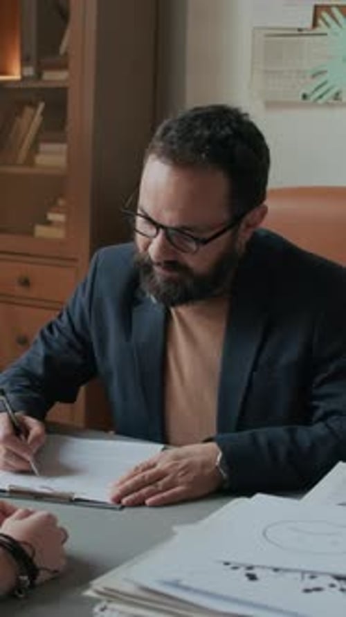 Professional Man Talking at Desk Writing Document