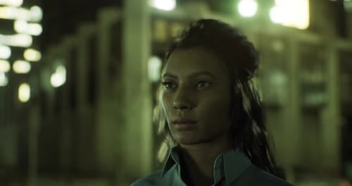 Jeune femme debout en toute confiance en milieu urbain la nuit avec des lumières incandescentes