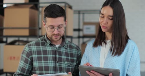 Closeup of a Female Manager Showing Information on a Tablet Computer to an Employee with a Cardboard