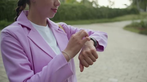 Gen Z Woman Setting Application on Smartwatch in City Park