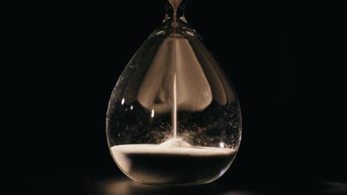 Elegant Hourglass Measuring Minutes in Dark Room Closeup Macro Sand Falling