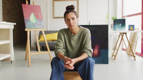 Video of of biracial female artist painting in studio