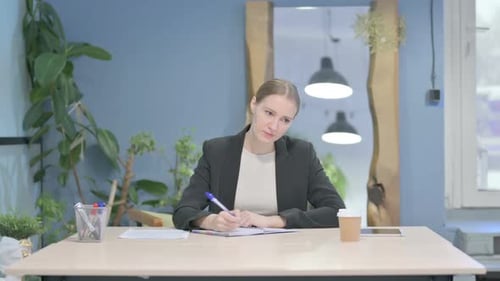 Businesswoman Writing while Sitting in Office