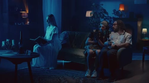 Woman Reads as Podcasters Record in Dimly Lit Room