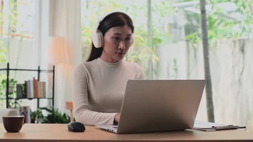 Woman Works at Laptop Wearing Headphones at Home