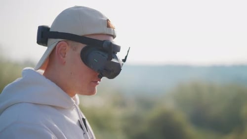 Rack focus transition from guy with FPV goggles to bright nature background