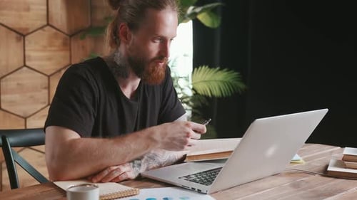 Man Video Conferencing on Laptop in Modern Office