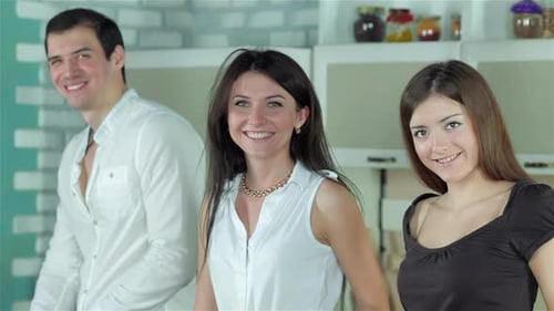 Drei Freunde bereiten sich ein gesundes Abendessen zu und lächeln direkt in die Kamera
