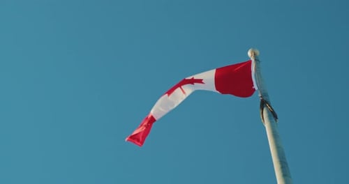 Canadian Flag Waving Against Blue Sky