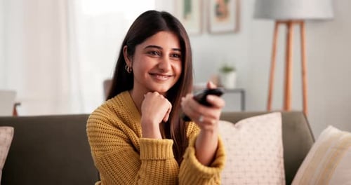 Woman Smiling and Holding Remote Control on Sofa