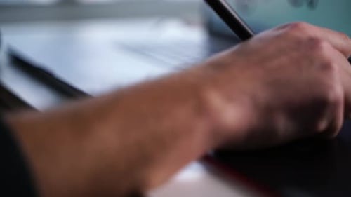 Adult Using Stylus on Graphics Tablet at Desk