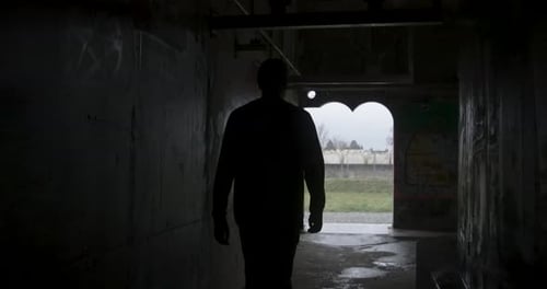 dark man walks through tunnel