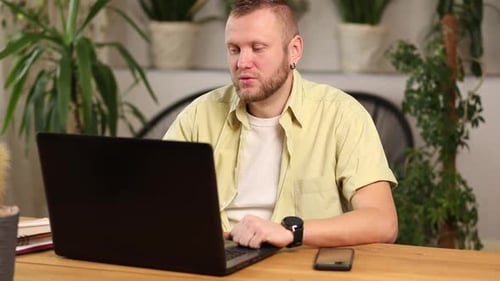 Man Works at Laptop in Bright Indoor Setting