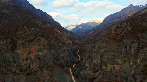 Drone shot of winding road between rocky mountains