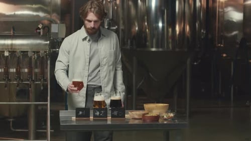 Man Inspecting Beer in Industrial Brewing Space