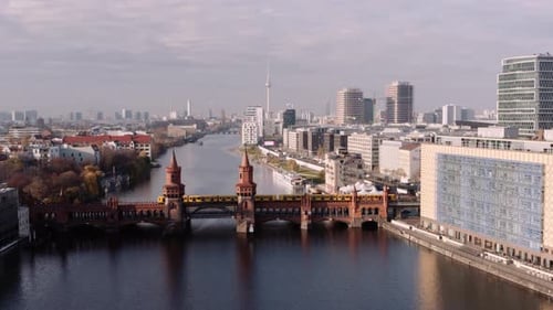 Aerial approach toward Oberbaum bridge with rapid transit train crossing, Berlin