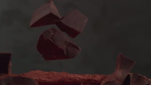 Chocolate Chunks Falling onto Cocoa Powder in Studio