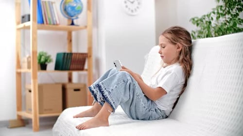 Girl Uses Cell Phone on White Sofa