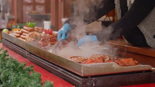 Street Vendor is Preparing Sausages on Grill at Christmas Market