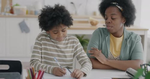 Woman Helping Child with Schoolwork at Home