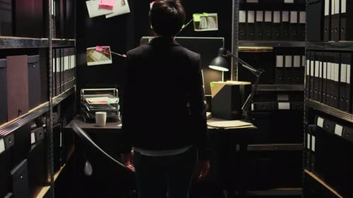 Investigator Walking Toward Investigation Desk in Dark Workplace