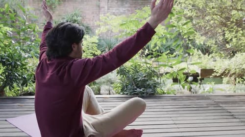 Caucasian man practicing yoga meditation on terrace in sunny nature, copy space, slow motion