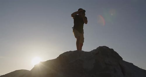 Young Attractive Photographer is Shooting a Landscape Edge of a Cliff at Sunset