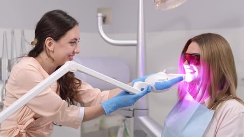 Dentist performing teeth whitening procedure on woman