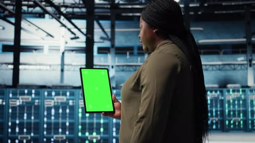 Rechenzentrumsspezialist überwacht Rechenzentrumsmetriken auf einem Greenscreen-Tablet