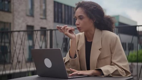 Woman Talks on Phone Working at Laptop Outdoors