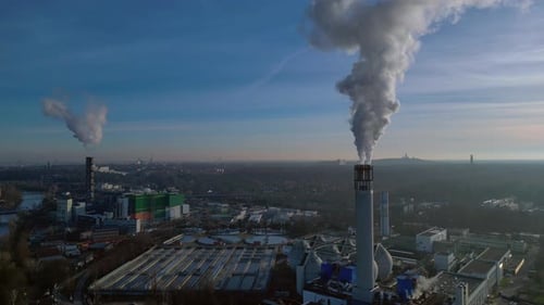 Waste to energy plant chimney emitting smoke into blue sky. Great aerial view drone