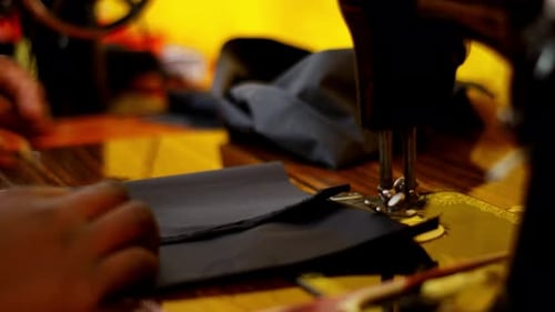 Woman in Africa using antique sewing machine to sew black fabric. Lady in Kenya working as seamstres