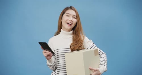 Woman Holding Package with Phone on Blue Background