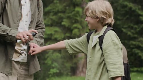 Dad and Son Using Mosquito Spray in Forest