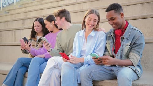 Friends Using Smartphones Together Outdoors on Concrete Steps